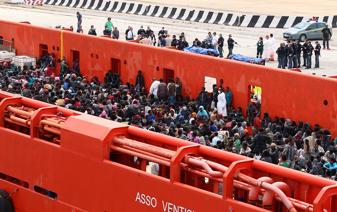 Hundreds of migrants are seen aboard an Italian Navy vessel before disembarking in the Sicilian port of Augusta.