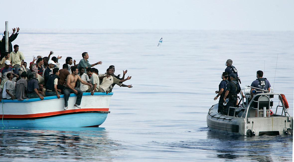 Members of the Maltese armed forces toss bottles of water to a group of around 180 illegal immigrants after their vessel ran into engine trouble