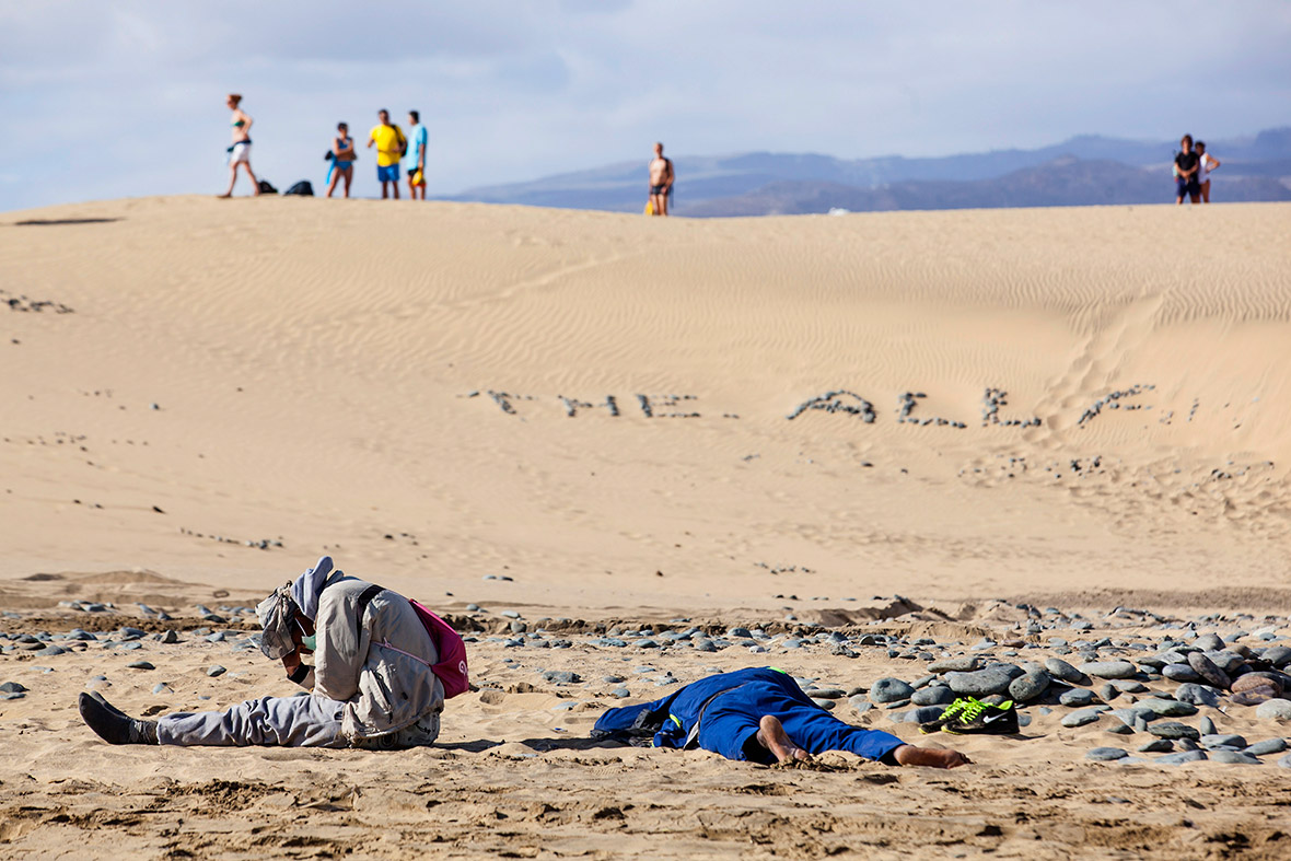 Two migrants rest at Maspalomas beach on Gran Canaria after travelling from Africa in a fishing boat.