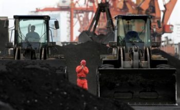 An employee walks between front-end loaders which are used to move coal imported from North Korea at Dandong port in the Chinese border city of Dandong