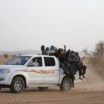 Migrants crossing the Sahara desert into Libya ride on the back of a pickup truck outside Agadez