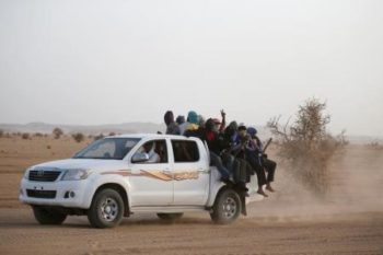 Migrants crossing the Sahara desert into Libya ride on the back of a pickup truck outside Agadez