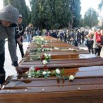 A man touches a coffin ahead of the funeral service for 26 Nigerian women who died last week while crossing the Mediterranean Sea, at the Salerno cemetery