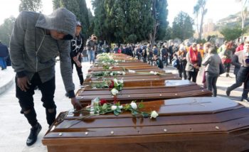 A man touches a coffin ahead of the funeral service for 26 Nigerian women who died last week while crossing the Mediterranean Sea, at the Salerno cemetery